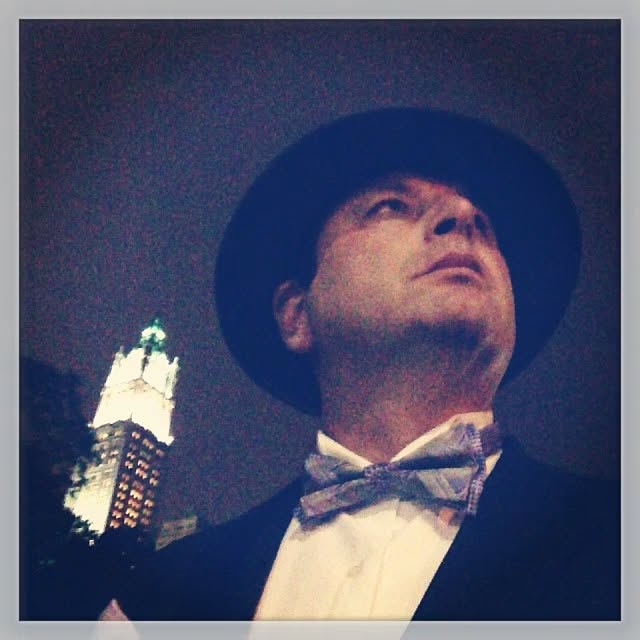 Steve in a hat and bow tie at night